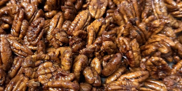 Close-up of glazed pecan nuts piled together.