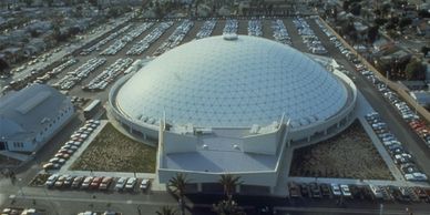 A large dome-shaped building with a glass roof surrounded by parking lots.