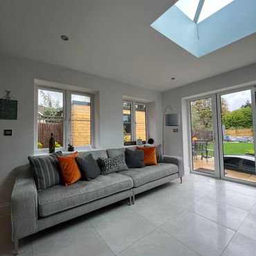 Large sofa in an open plan kitchen / dining area with with a grey and orange colour pallette