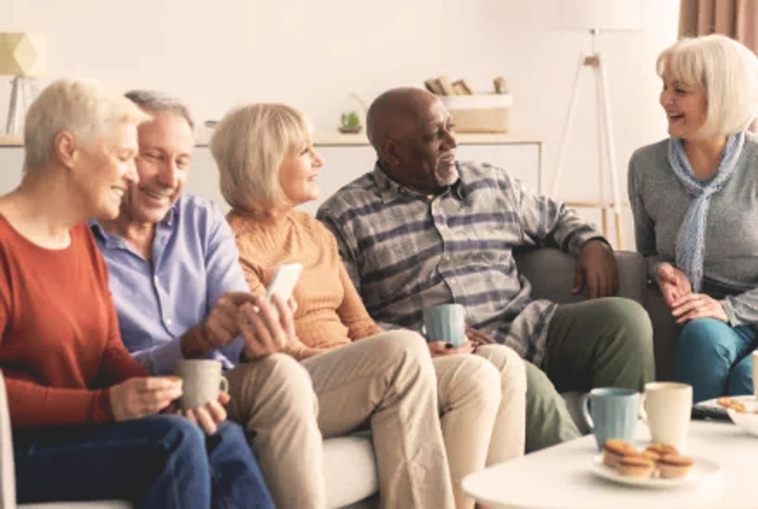 A group of elderly friends enjoying coffee and conversation at home.