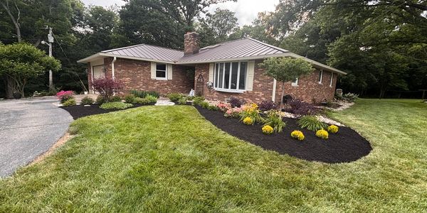 Brick house with fresh mulch and flower beds in front yard.