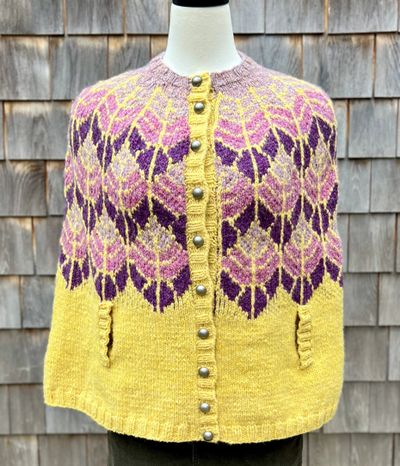 Colorful knitted cardigan with purple and pink leaf patterns on yellow background.