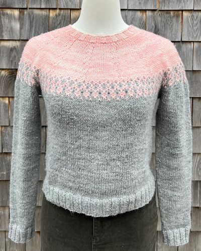 Knit sweater with gray body and pink patterned top.