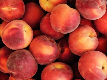 A pile of fresh ripe peaches with reddish-yellow skin.