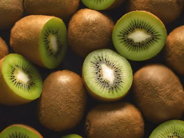 Fresh whole and halved kiwis showing their green interiors.