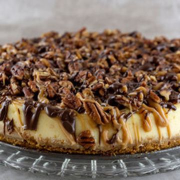 Creamy pecan cheesecake topped with chocolate and caramel drizzle.