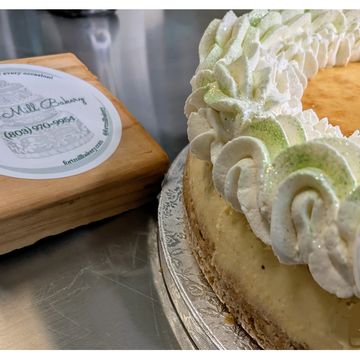 Close-up of a cheesecake with whipped cream and green sprinkles.