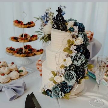 Three-tier white cake with floral decorations and desserts.