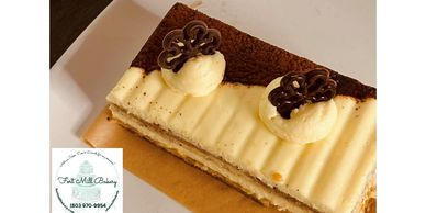 Elegant layered dessert with cream and chocolate decorations on a white plate.