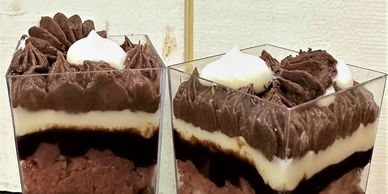 Two layered chocolate and cream desserts in clear cups.