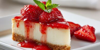 Cheesecake slice topped with fresh strawberries and strawberry sauce.