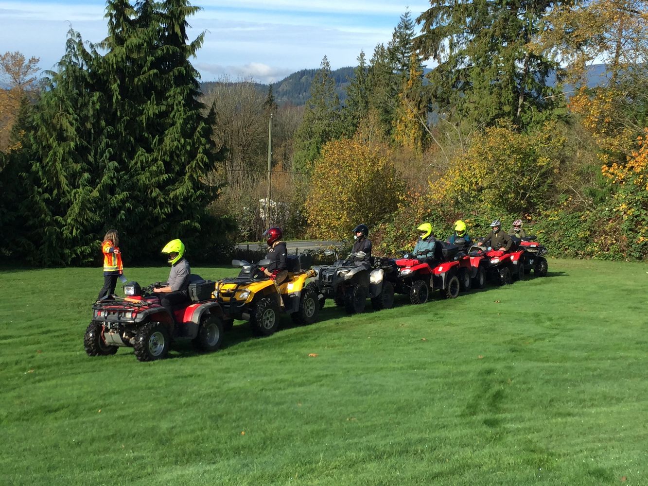 A line of people on ATVs listening to an instructor.