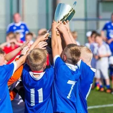 Kids in blue jerseys holding a trophy.