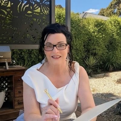 Woman in white dress holding a pen and paper outdoors.