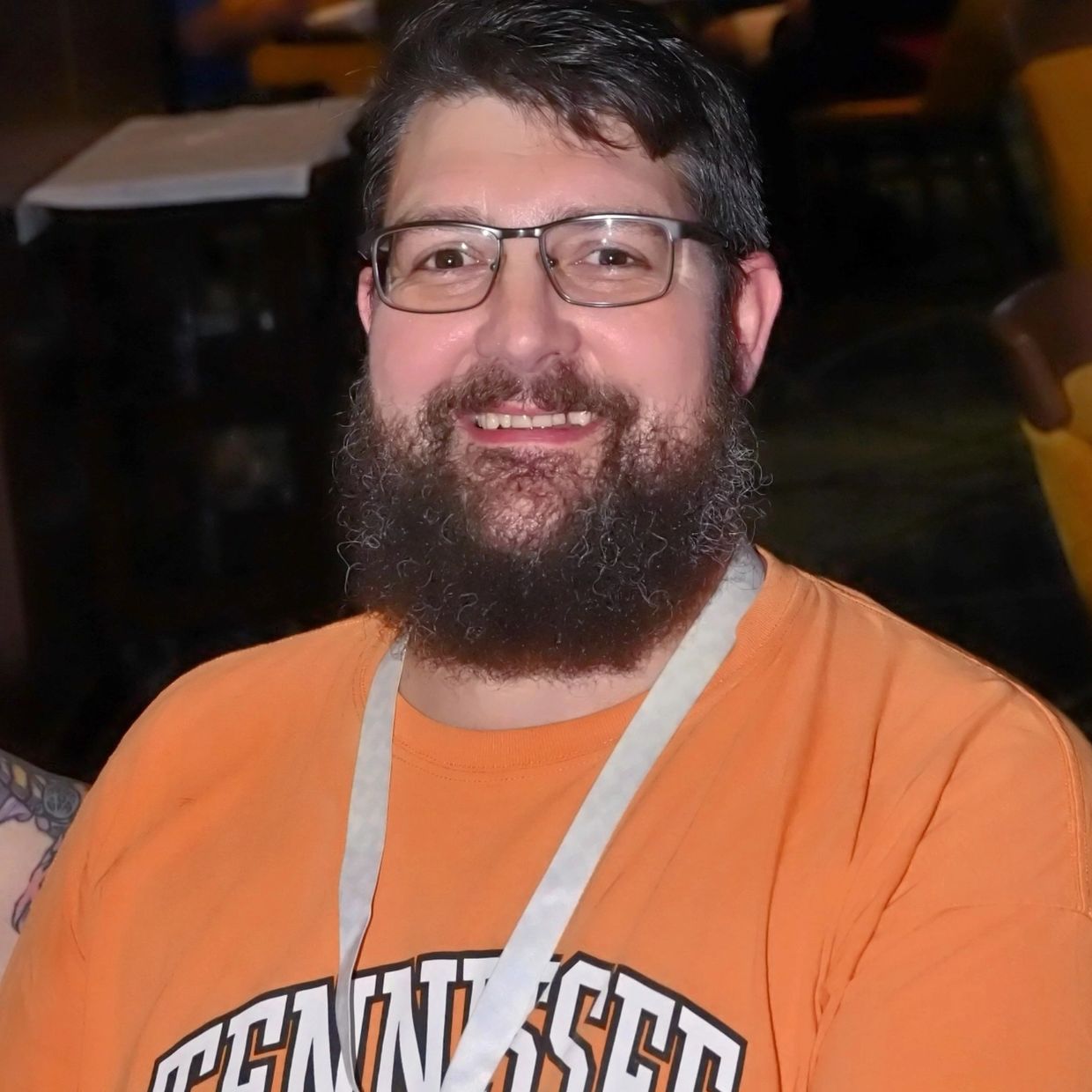 Smiling man with glasses and a beard wearing a Tennessee t-shirt.