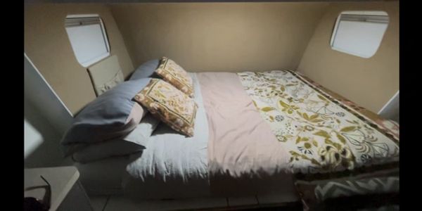 Cozy bed with patterned pillows and floral bedding in a small room with windows.