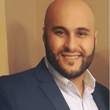 Smiling man in a blue suit jacket and white dress shirt.