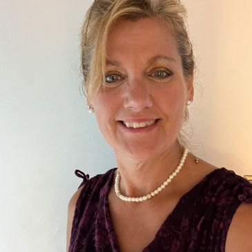 Smiling woman with pearl necklace and elegant dress.