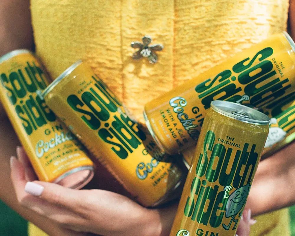 Person holding multiple South Side canned cocktails.