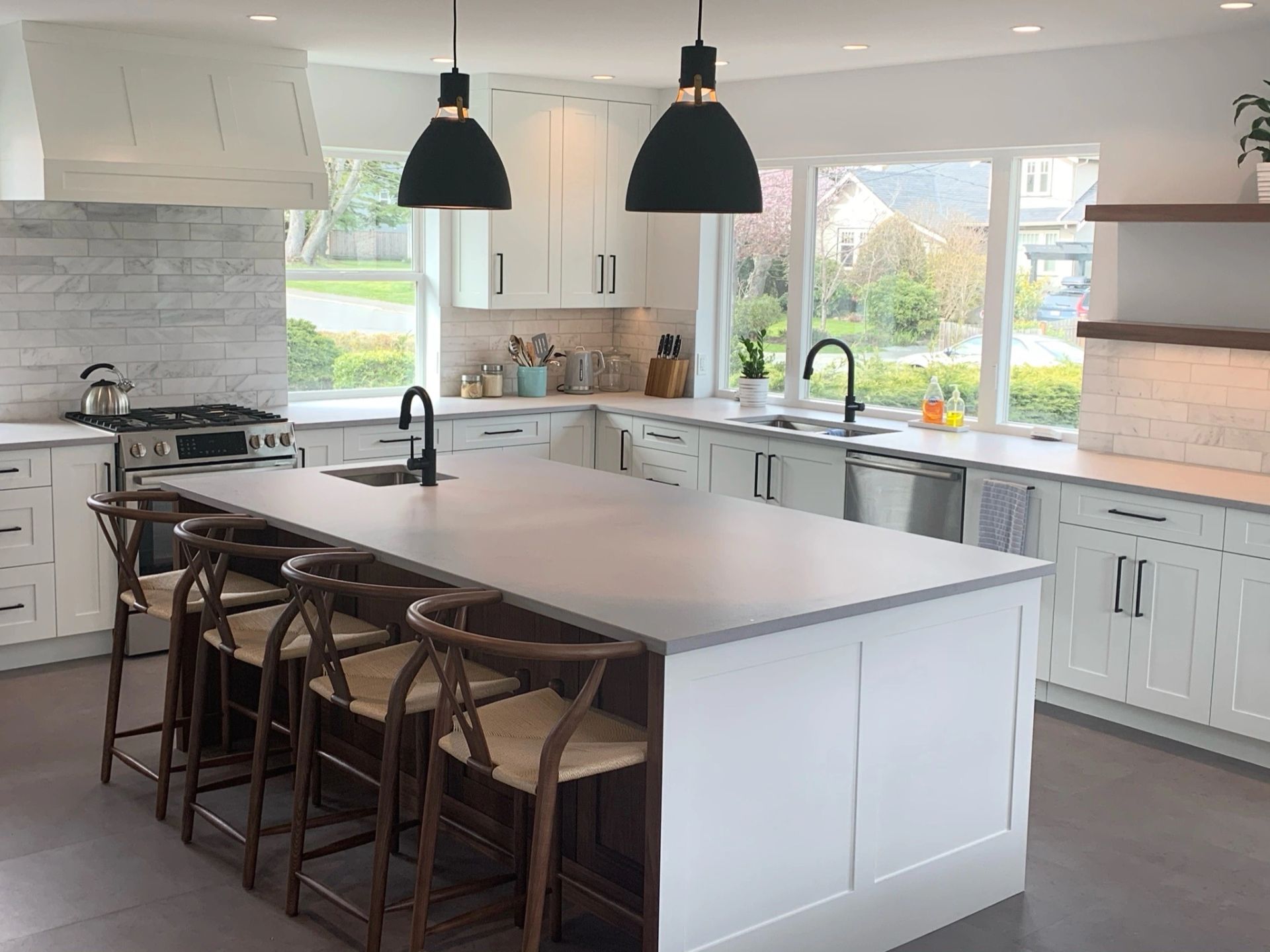 Bright white shaker kitchen with a quartz island and black pendant lights, built by DM Patterson Construction in Victoria BC