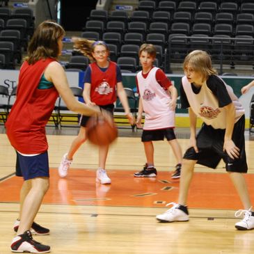 Kids playing basketball in a gymnasium during a practice game.