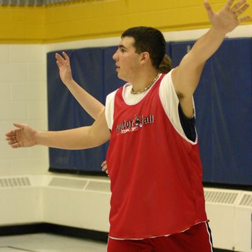 Basketball player in red jersey defending with arms wide open indoors.