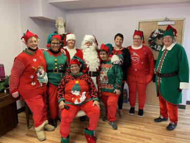Group dressed in colorful Christmas sweaters and Santa costumes.