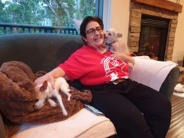 Woman smiling with two dogs on a couch.
