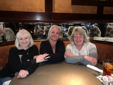 Three women sitting at a restaurant table smiling.