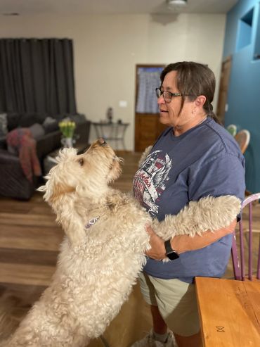 Woman holding a large dog in a living room.