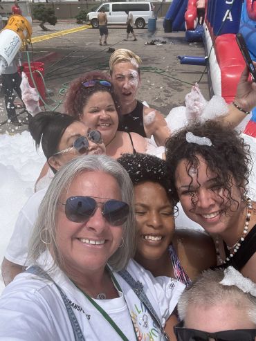 Group of friends enjoying a foamy outdoor activity.