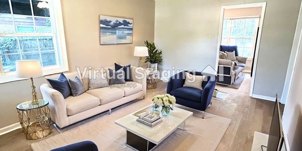Modern living room with blue armchairs, beige sofa, and white coffee table on a light rug.