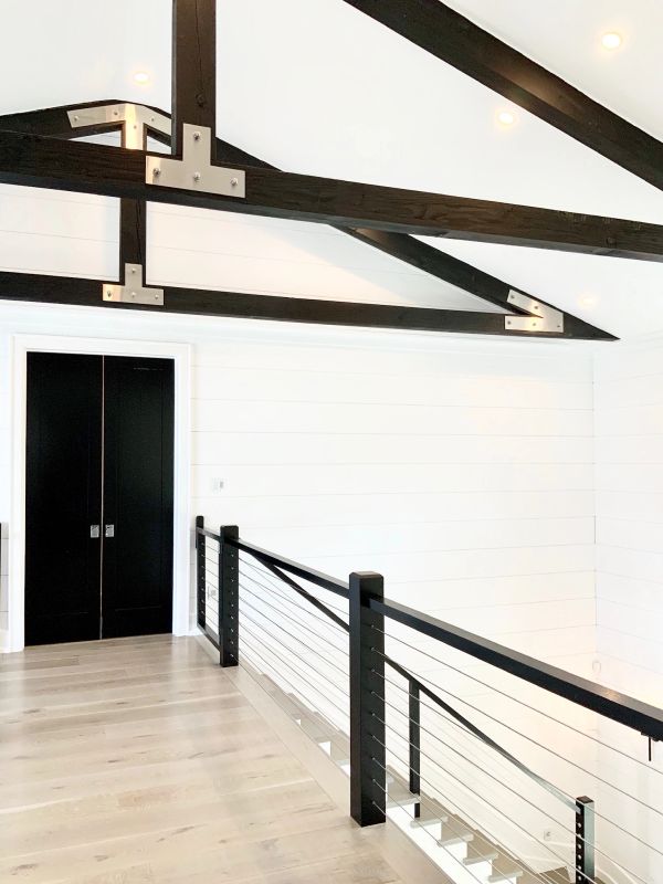 Modern interior with black beams and railing.