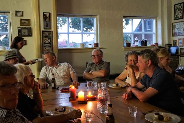 Menschen sitzen an einem Tisch, trinken und unterhalten sich.