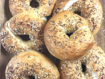 Freshly baked everything bagels on a wooden surface.
