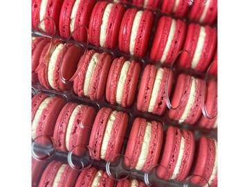 Rows of red and white macarons neatly arranged in clear packaging.