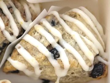 Blueberry scones with white icing drizzle in a box.