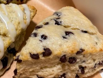 Close-up of a blueberry scone with icing on another scone.