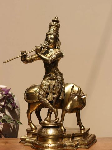 Intricately detailed brass statue of Lord Krishna playing flute with a cow.