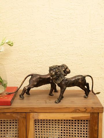 Bronze lion statues on a wooden cabinet against a textured wall.