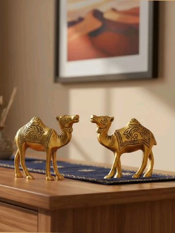 Two ornate golden camel figurines on a wooden table with desert art in the background.