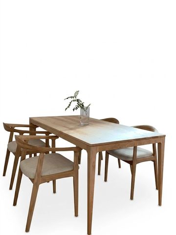 Wooden dining table with four chairs and a glass vase with greenery.