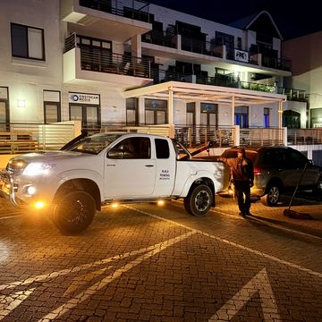 White pickup truck parked outside a building at night with a person nearby.