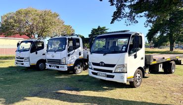 Three MHD Transport 4-ton trucks parked together on an open field on a sunny day.