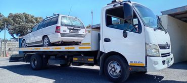 Roadside breakdown towing of a compact vehicle on a flatbed truck in Cape Town.