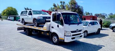 Flatbed tow truck loading a white bakkie for roadside recovery in Cape Town.