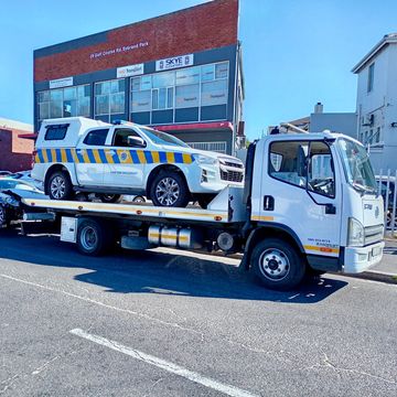 A police vehicle on a tow truck on a sunny street.