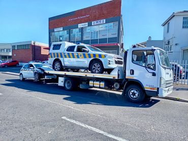 MHD Transport truck transporting a bakkie and car parked Infront of our office in the road.