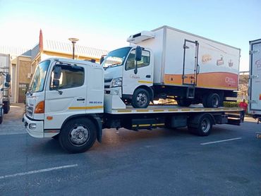 White MHD Transport truck loaded with another truck parked in the road.