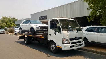Flatbed towing service collecting a Hyundai SUV from a dealership in Cape Town.